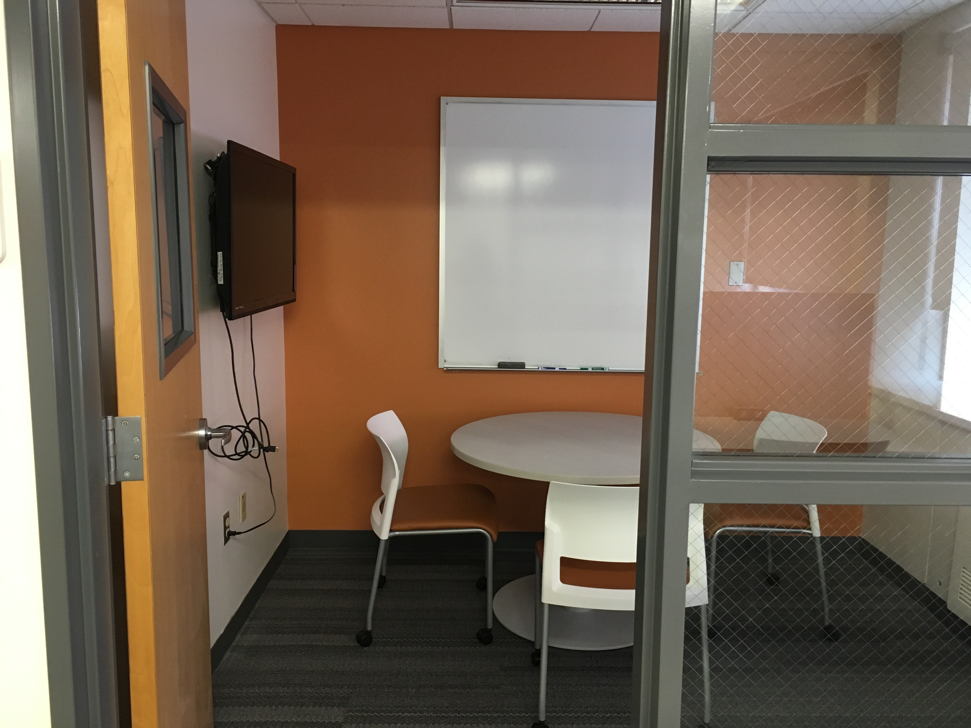 A study room with a table, three chairs and a white board